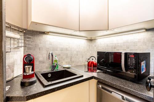 une cuisine avec un évier et un micro-ondes dans l'établissement GuestReady - Stone wall stay near Sainte-Chapelle, à Paris