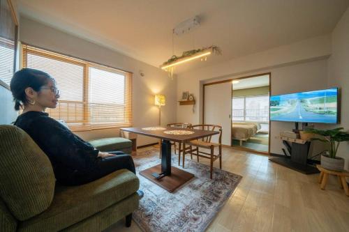 a woman sitting on a couch in a living room at W401 Near the center of Sapporo, Japanese style in Sapporo
