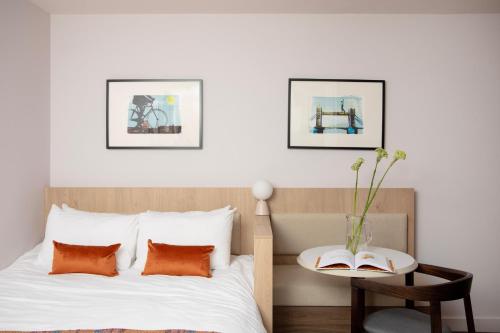 a bedroom with a bed with orange pillows and a table at Bob W London Tower Hill - Residences in London