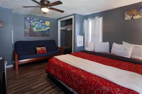 a bedroom with a red bed and a blue couch at Pool-Table-Hot Tub-Fire Pit in Glasgow