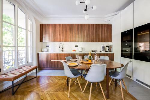 - une cuisine avec une table en bois et des chaises blanches dans l'établissement GuestReady - Apt Familial près de la Tour Eiffel, à Paris