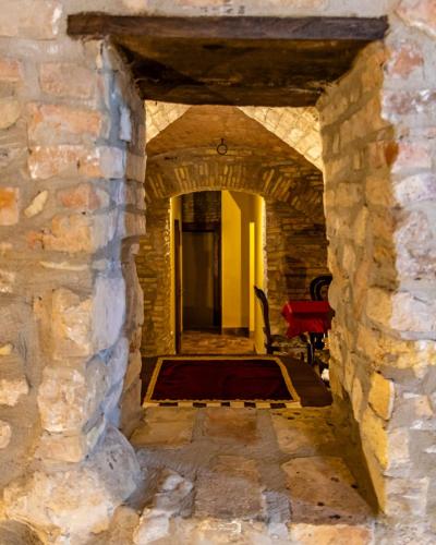 an archway in a stone building with a red chair at Castello di Petecciano B&B in Mosciano SantʼAngelo