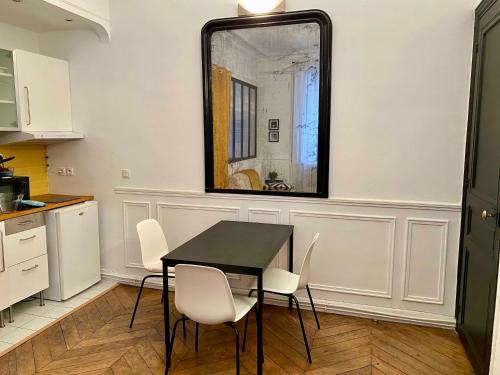 - une table et des chaises dans une cuisine avec un miroir dans l'établissement Charmant appartement Paris 8., à Paris