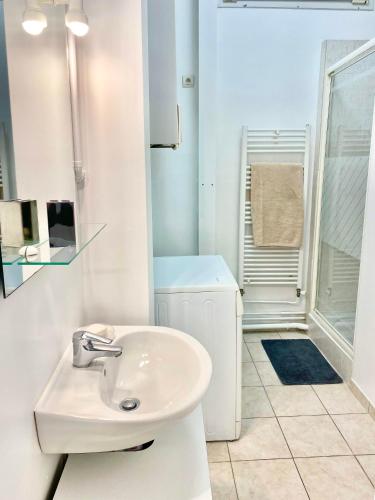 une salle de bain blanche avec un lavabo et une douche dans l'établissement Charmant appartement Paris 8., à Paris