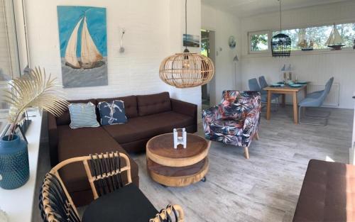 una sala de estar con un sofá y una mesa en Strandnahes Ferienhaus mit Wintergarten, grosser uneinsehbarer Garten, komplett eingezäunt, en Sint Maartensvlotbrug