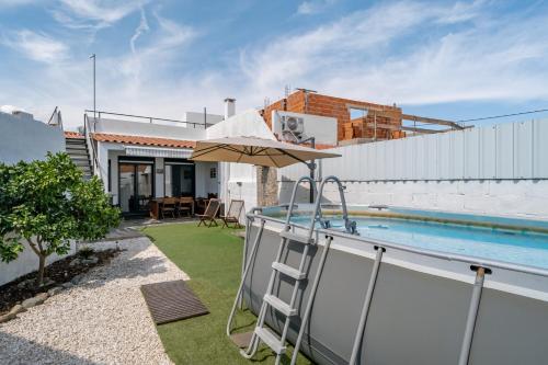 a house with a swimming pool and an umbrella at Campinhus in Campinho