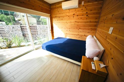 - une chambre avec un lit bleu dans un mur en bois dans l'établissement ビーチキャビン - シービュー バーベキュー ピザ サウナ プール ホットタブ - Beach Cabin Chiba - Seaview BBQ Pizza Sauna Pool Hot-tub, à Kobama