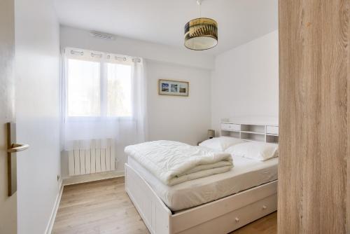 une chambre blanche avec un lit et une fenêtre dans l'établissement Proche du marché et de la grande plage de l'Ecluse, à Dinard
