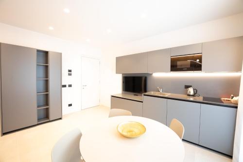 a white kitchen with a white table and chairs at Midum LuxuryApartments con giardino in Trento