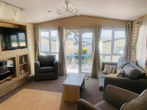 a living room with a couch and a tv and a table at Rockley Park Haven in Lytchett Minster