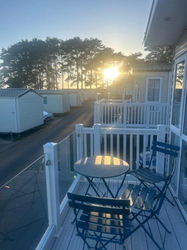 a table and two chairs on a porch with the sunset at Rockley Park Haven in Lytchett Minster