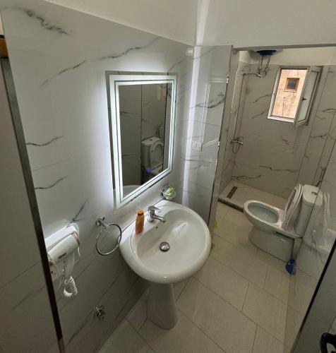 a white bathroom with a sink and a toilet at Hotel Freskia in Gjirokastër