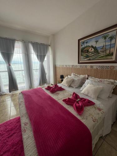 a bedroom with a large bed with red bows on it at Pousada toca do cambu in Angra dos Reis