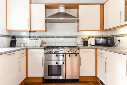 a kitchen with white cabinets and a stainless steel stove at Spacious Townhouse Private Parking Central Wells in Wells
