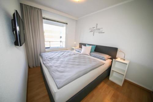 a bedroom with a bed with a television and a window at Ferienwohnung Koje 117 im Haus Carpe Diem in Niendorf