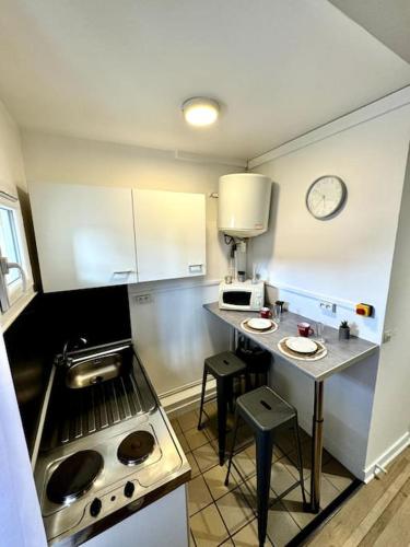 レシニーにあるStudio en plein centre-villeの小さなキッチン(テーブル、壁掛け時計付)