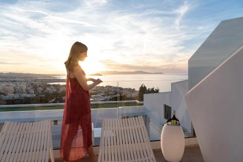 a woman in a red dress standing on a balcony at Lagon Life Spirit Boutique Hotel - Adults Only in Chania Town