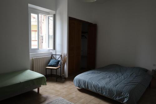 une chambre avec un lit, une chaise et une fenêtre dans l'établissement Gite les kiwis, à Bessèges