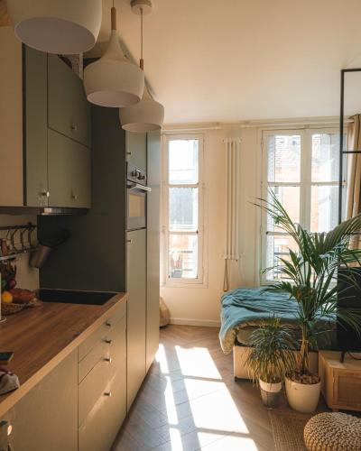 une cuisine avec des armoires vertes et des plantes en pot dans l'établissement Appartement Studio Paris La Défense, à Suresnes