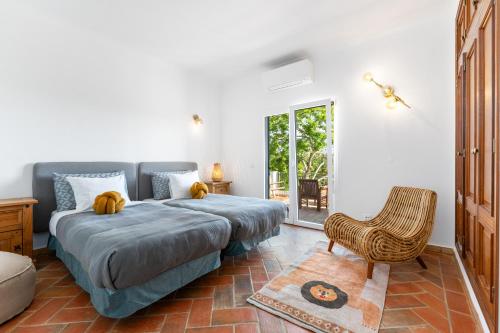 a bedroom with a bed and a chair at Luxury Casa Madeira, HEATED Salt Water Pool and Panoramic Woodfire Sauna in Lagos