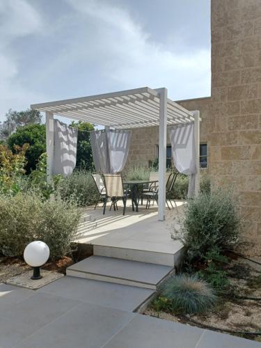 a pergola with a table and chairs on a patio at Zeituna Lodge a Porto Cesareo in Torre Lapillo