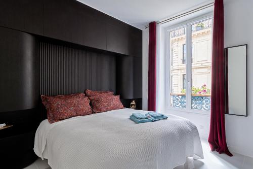 Cette chambre comprend un grand lit avec des oreillers rouges et une fenêtre. dans l'établissement Champs-Élysées Executive Apartment, à Paris