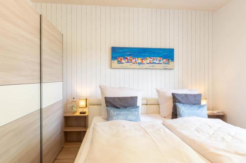 a bedroom with a large white bed with blue pillows at Ferienhaus Eastside - Niendorf in Häven