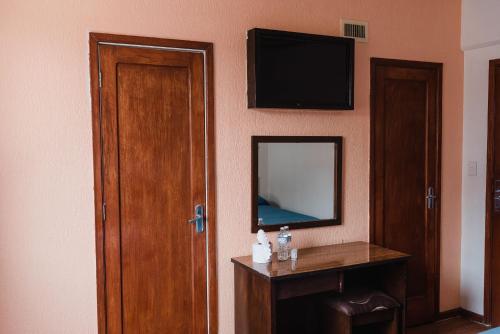 Habitación con TV en la pared y mesa. en Hotel Rex, en Toluca