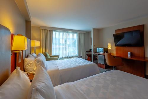 a hotel room with two beds and a flat screen tv at Holiday Inn San Jose La Sabana by IHG in San José