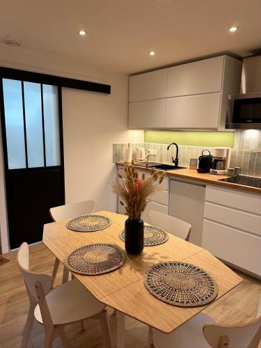- une cuisine avec une table et des chaises en bois dans l'établissement Les Meublés de Luchon - L'échappée verte - Centre Luchon, Calme, Wifi, à Luchon