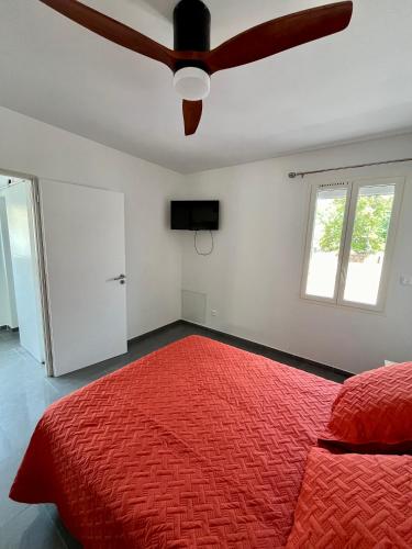 - une chambre avec un lit rouge et un ventilateur de plafond dans l'établissement Villa Maurice, à Valras-Plage