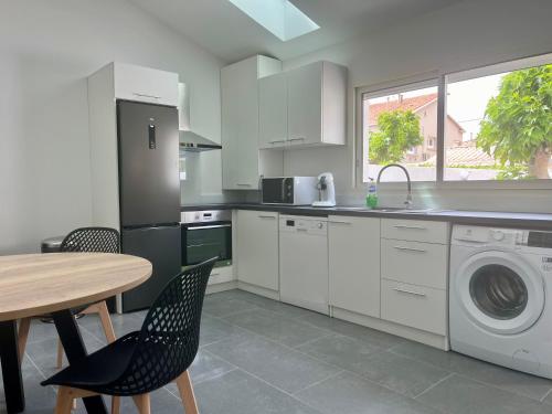 une cuisine avec une table et une machine à laver dans l'établissement Villa Maurice, à Valras-Plage