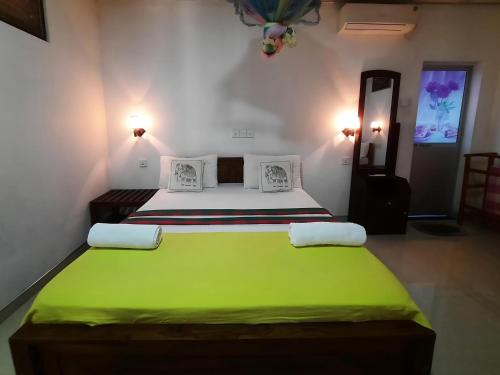 a bedroom with a large bed with a green blanket at Batu's Safari lodge Udawalawe in Udawalawe