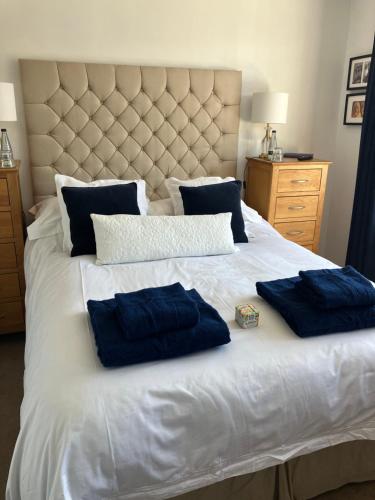 a white bed with two blue pillows on it at Our beautifully renovated home in Chichester