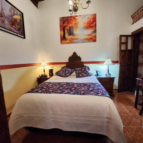 a bedroom with a large bed with two lamps at HOTEL CASA BAEZ in Pátzcuaro