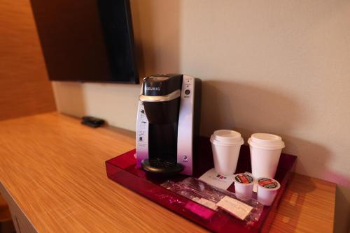 a coffee maker and two cups on a table at Le Fabreville Motel & Suites in Laval
