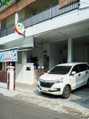 a white car parked in front of a building at Anjuma Backpacker in Yogyakarta