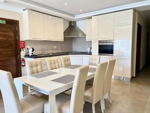 a white kitchen with a white table and chairs at San Anton Gardens 3BDR Apartment in Balzan