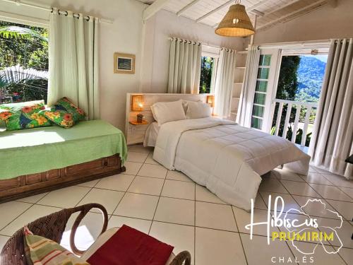 a bedroom with a bed and a table and chairs at Hibiscus Prumirim Chalés in Ubatuba