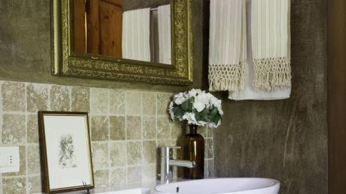 a bathroom with a sink and a mirror and a vase of flowers at Villa Il Colto in Terranuova Bracciolini