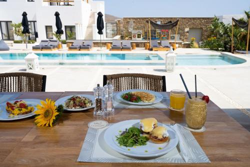 a table with plates of food next to a swimming pool at Le Palme Mykonos in Klouvas