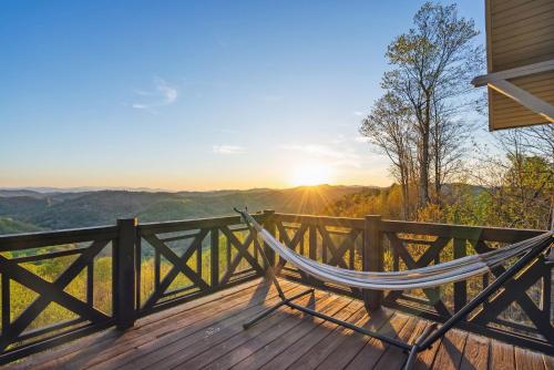 a hammock on a deck with the sunset in the background at 2 Cabins & Views for Miles Hot Tubs Pool Table in Swiss