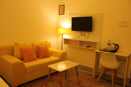 a living room with a couch and a desk with a television at The Nandi International Boutique Stay in Varanasi