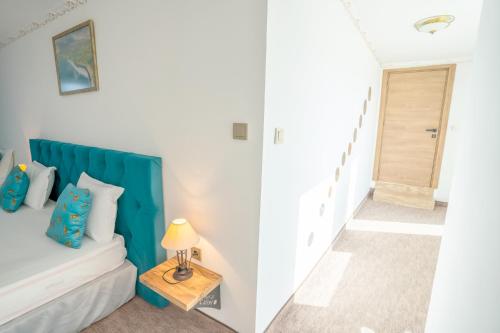 a room with a bed with a blue headboard and a hallway at Royal Calisto Hotel in Sozopol