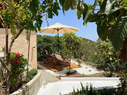 a patio with an umbrella and a table and chair at The Garden House, Sitia in Sitia