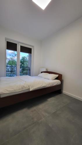 a bedroom with a large bed and two windows at Atlas Arena Apartament in Łódź