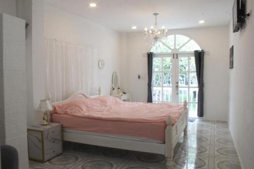 a bedroom with a pink bed and a window at Bananaleaf Wedding Cafe & Resort in Ban Bang Kaeo