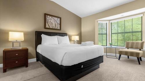 a bedroom with a large bed and a chair at Book Your Summer Escape - TownHome by Disney! in Orlando