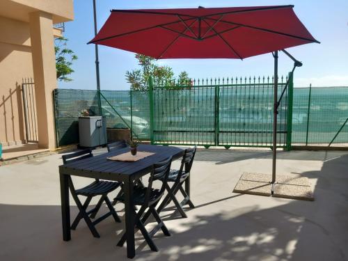 a black table and chairs with a red umbrella at La Perla del Mare in Pisciotta