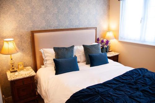 a bedroom with a large bed with blue pillows at 2 bedroom house in Chichester near Goodwood and Wittering beaches in Chichester